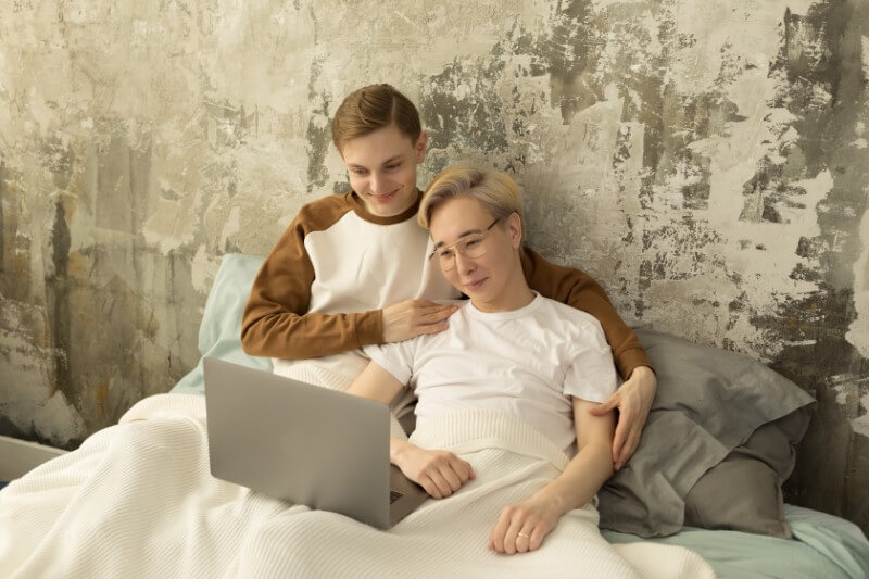 schwules Pärchen schaut Film auf Laptop im Bett