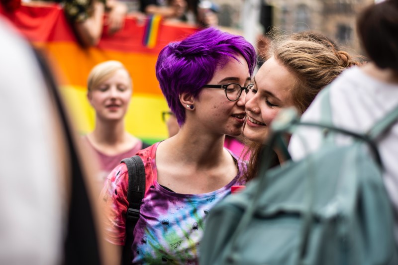 zwei junge Mädchen küssen sich bei einem Pride-Marsch.
